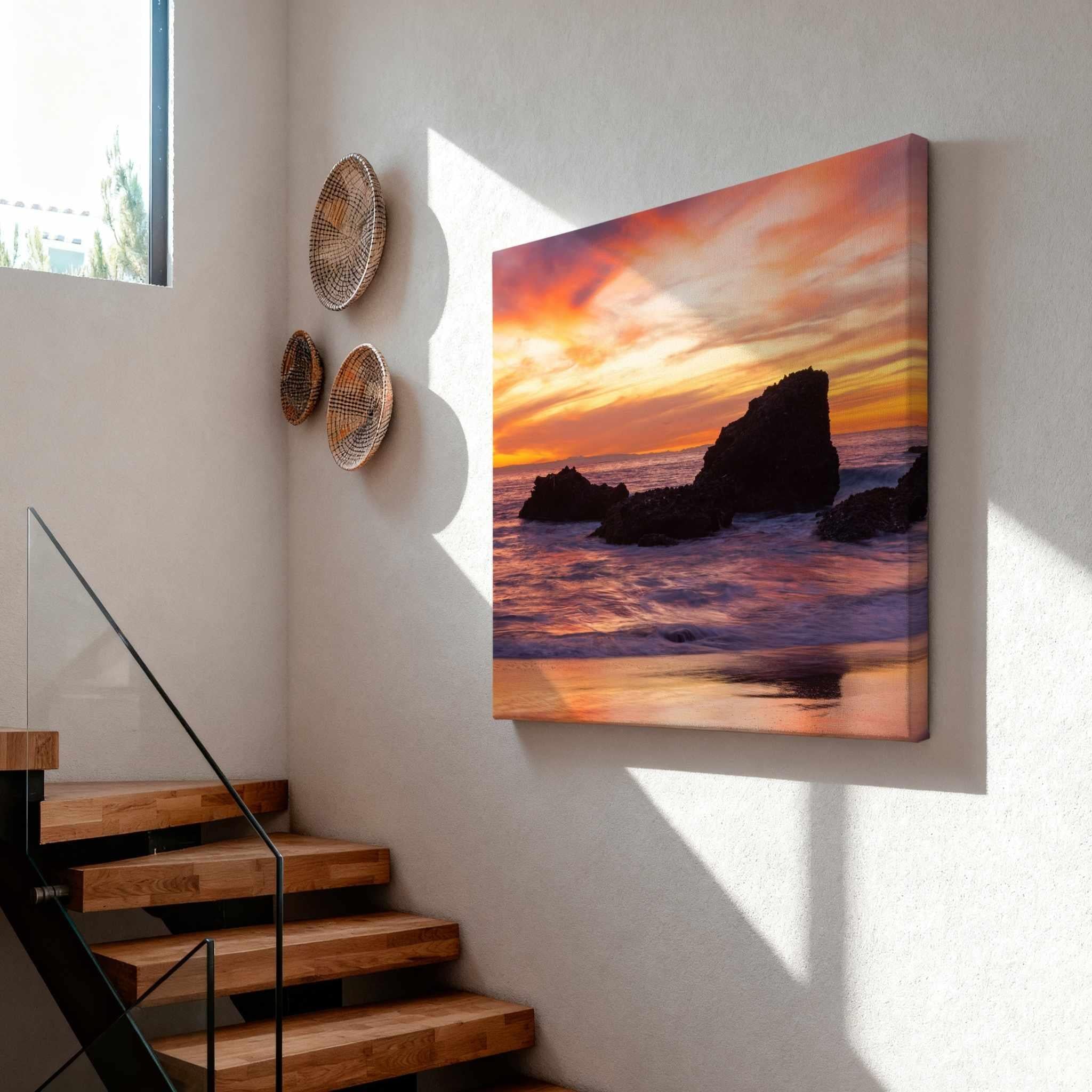 Sherbet Sunset canvas wall art displayed on a modern staircase wall, showcasing glowing orange and pink sunset skies over the Pacific Ocean at Laguna Beach, California.