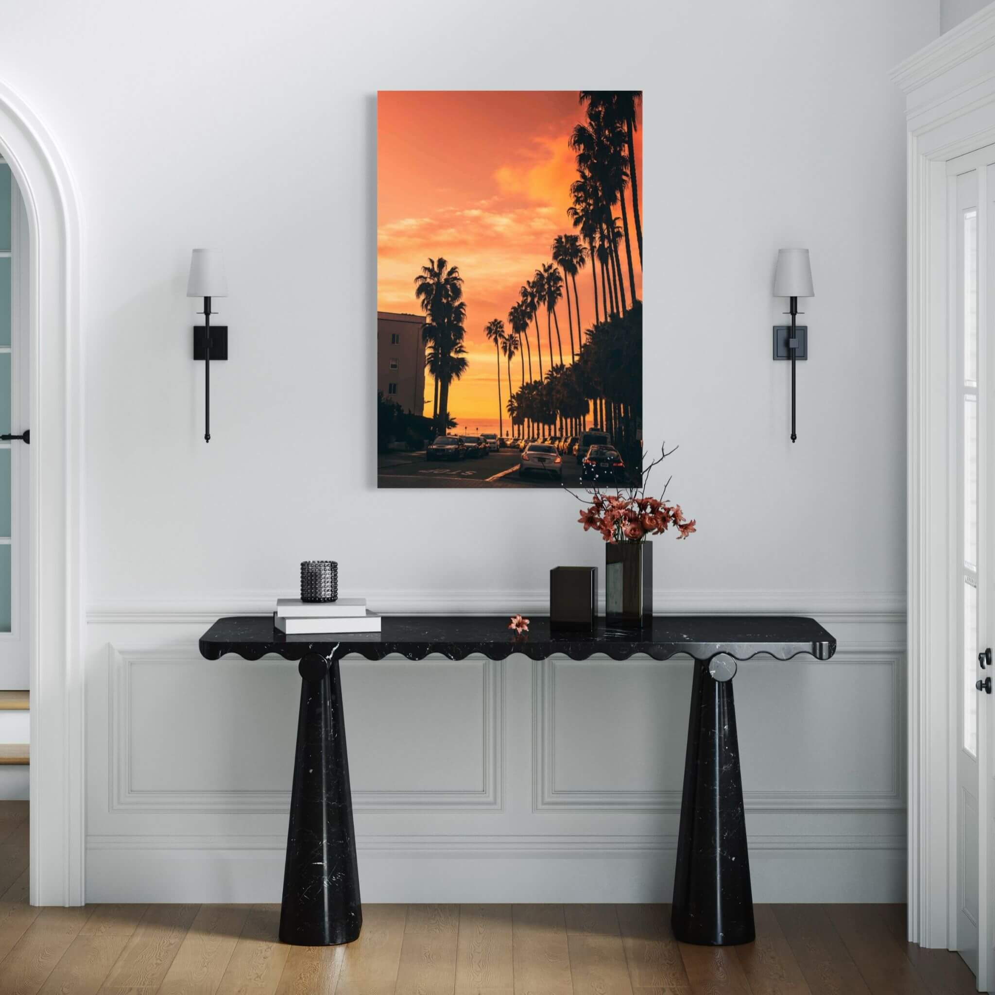 Sizzling Hot San Diego Nights metal print with orange sunset and palm trees displayed above a black console table in a bright contemporary entryway.