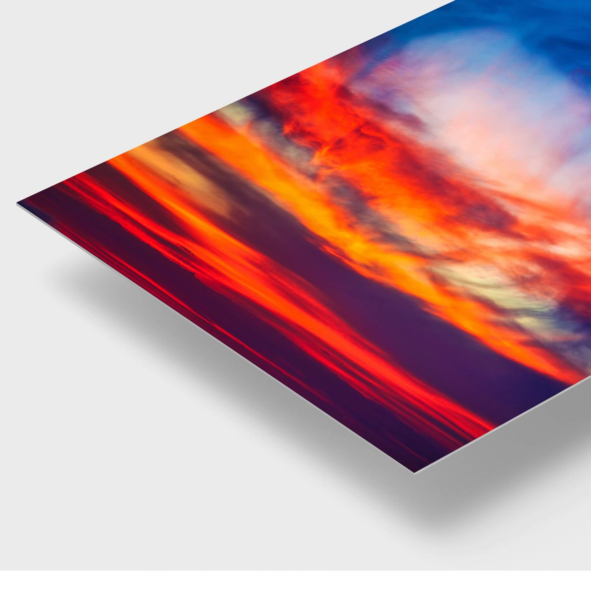 Close-up detail of the Smoldering Clouds high-definition metal print by Abigail Diane Photography, highlighting the slim contemporary profile and vibrant cobalt blue, crimson red, fiery orange, violet, and luminous golden tones of a dramatic Southern California sunset over the Pacific Ocean.