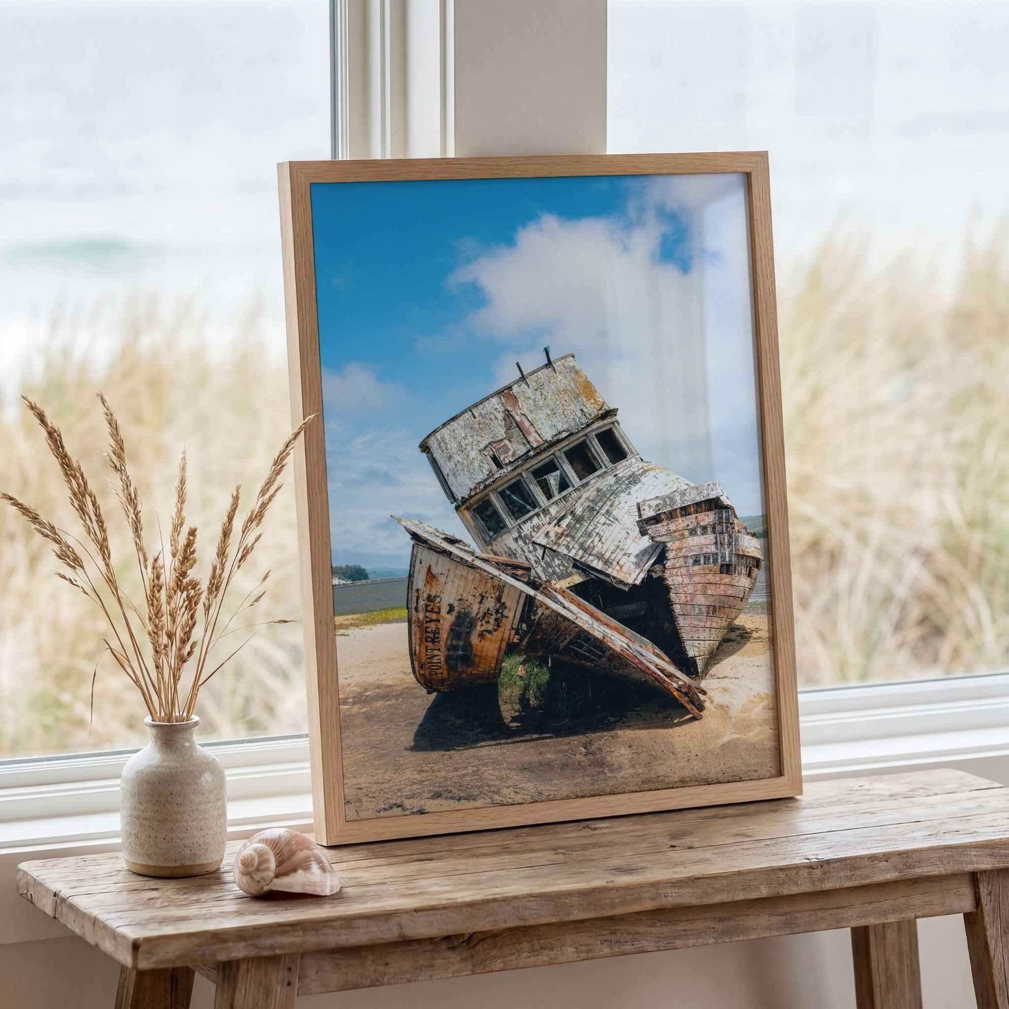 Framed S.S. Point Reyes shipwreck photograph displayed on a rustic coastal table beside dune grass and seashell décor, fine art photography by Abigail Diane Photography.