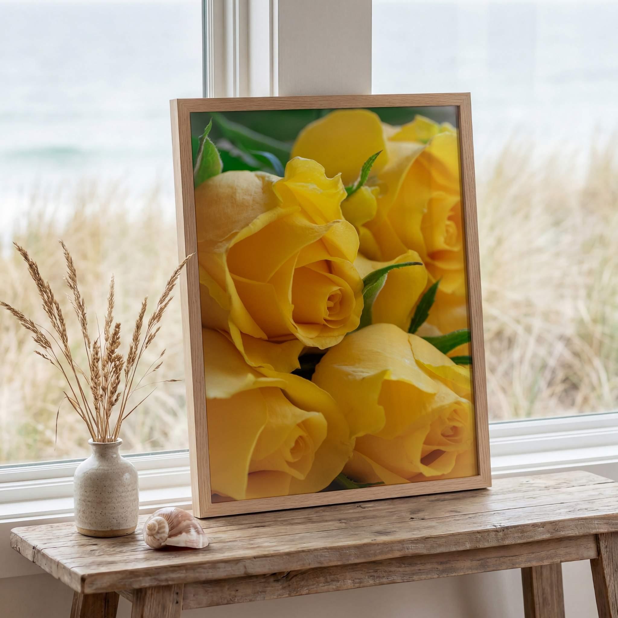 Sunlit Petal Reverie yellow rose fine art photography by Abigail Diane Photography displayed in a natural oak frame on a rustic coastal table beside beach grass, seashell accents, and soft ocean views.