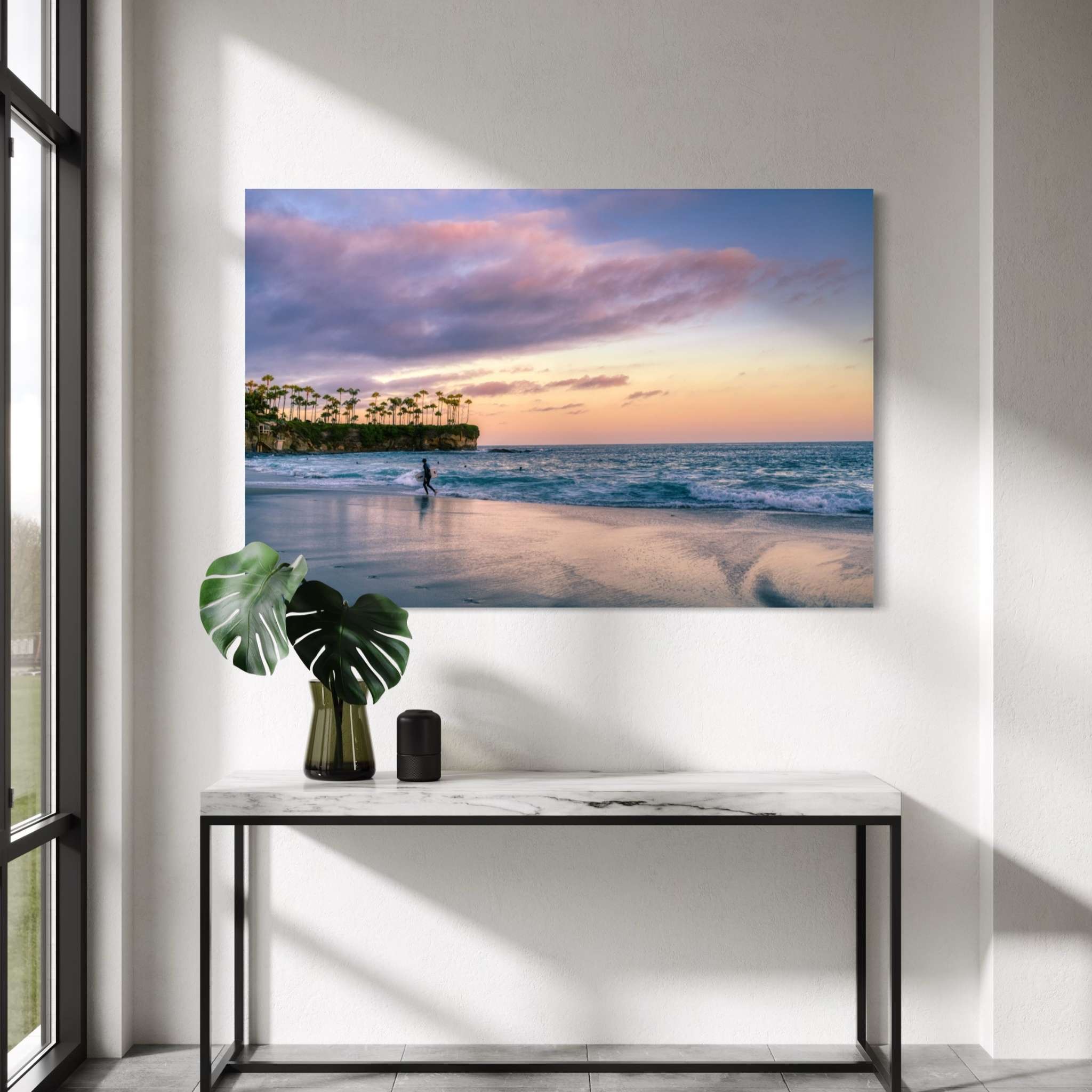 Surfing a California Sunset metal print displayed above a marble console table in a modern entryway, featuring Crescent Beach, Laguna Beach, California. Artwork by Abigail Diane Photography.