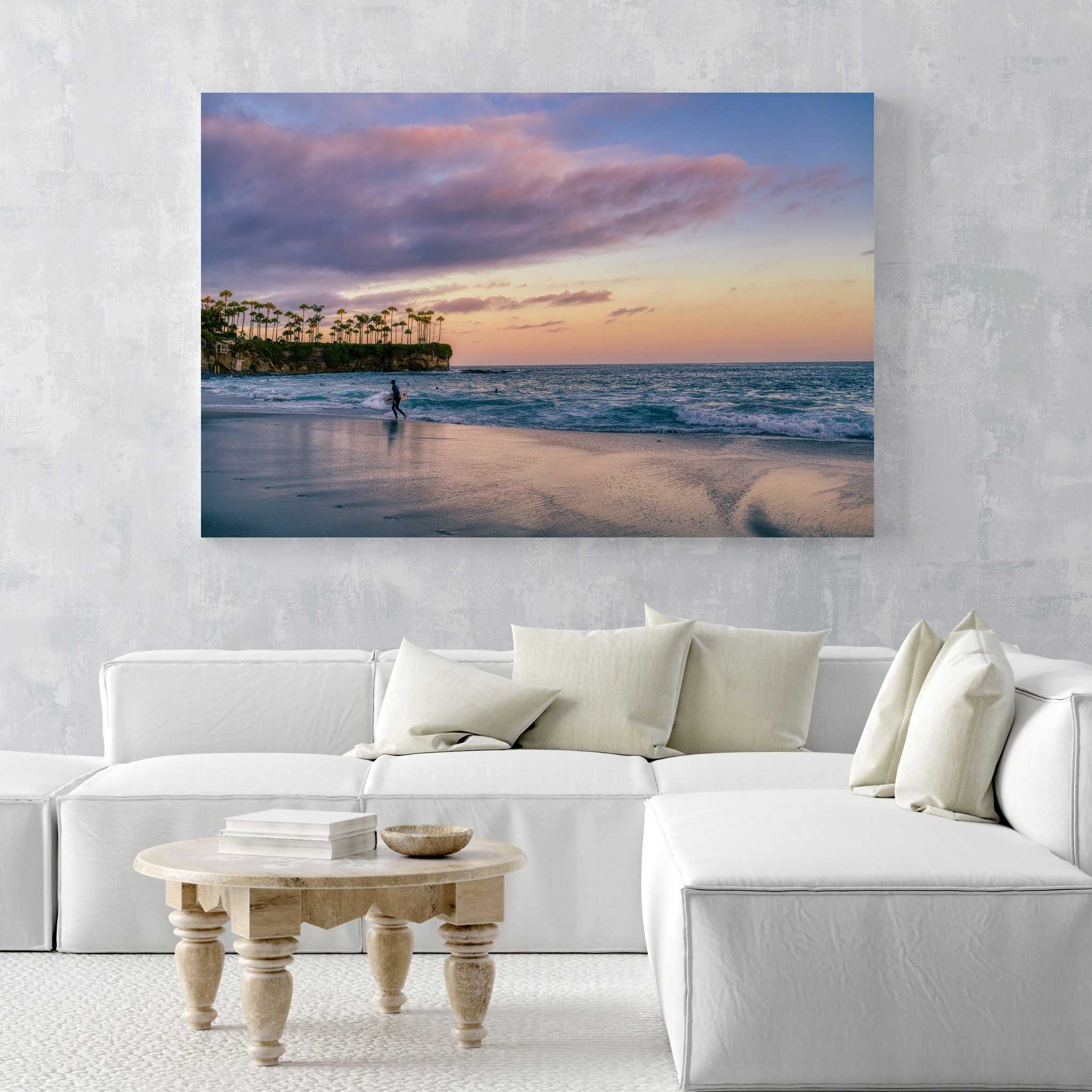Surfing a California Sunset dye-sublimation metal print displayed above a white sectional sofa in a modern coastal living room, featuring Crescent Beach, Laguna Beach, California. Artwork by Abigail Diane Photography.
