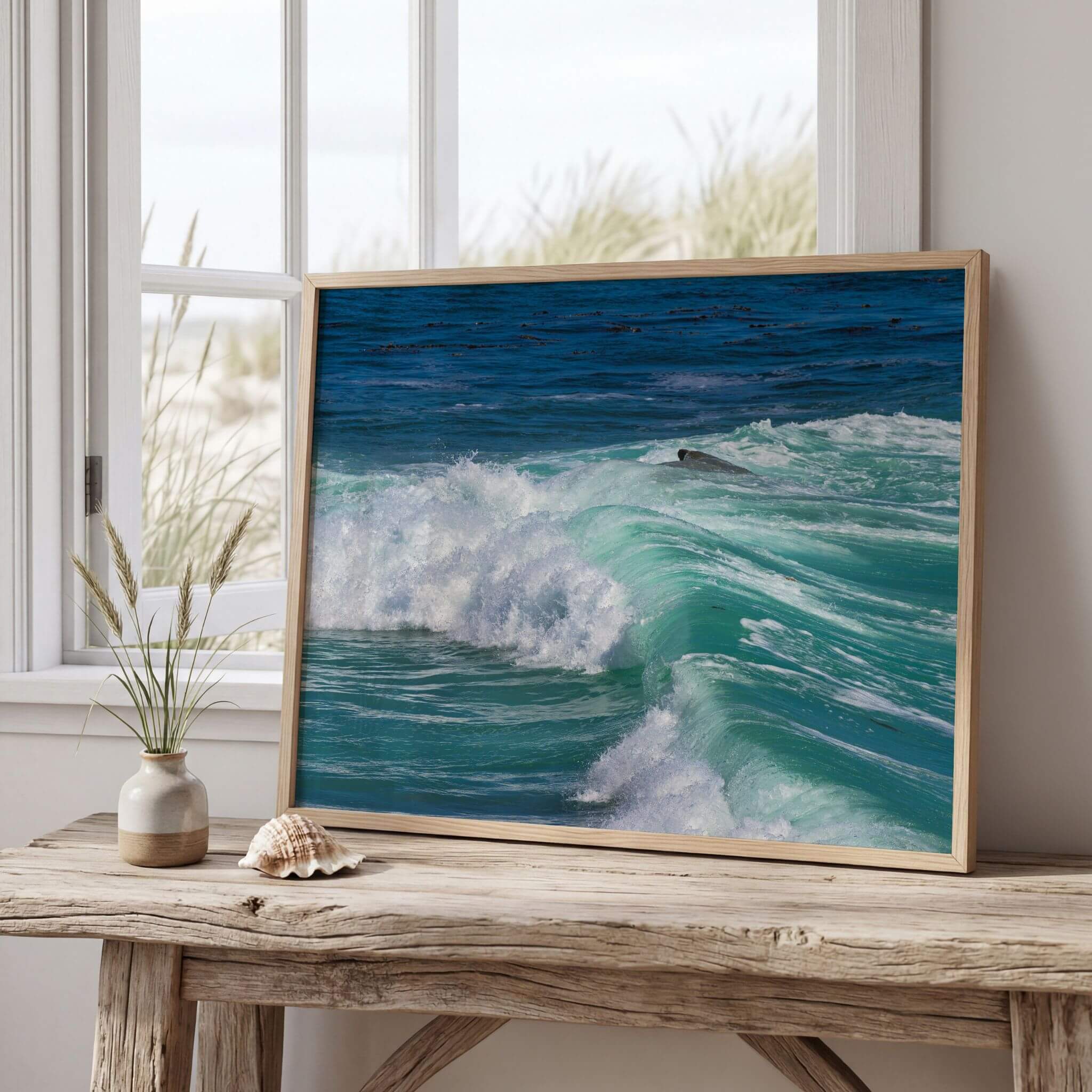 Framed Turquoise Healing Waves print leaning on a rustic wooden table beside a bright window, highlighting the rolling turquoise waves of the Pacific Ocean in Laguna Beach, California. Fine art photography by Abigail Diane Photography.