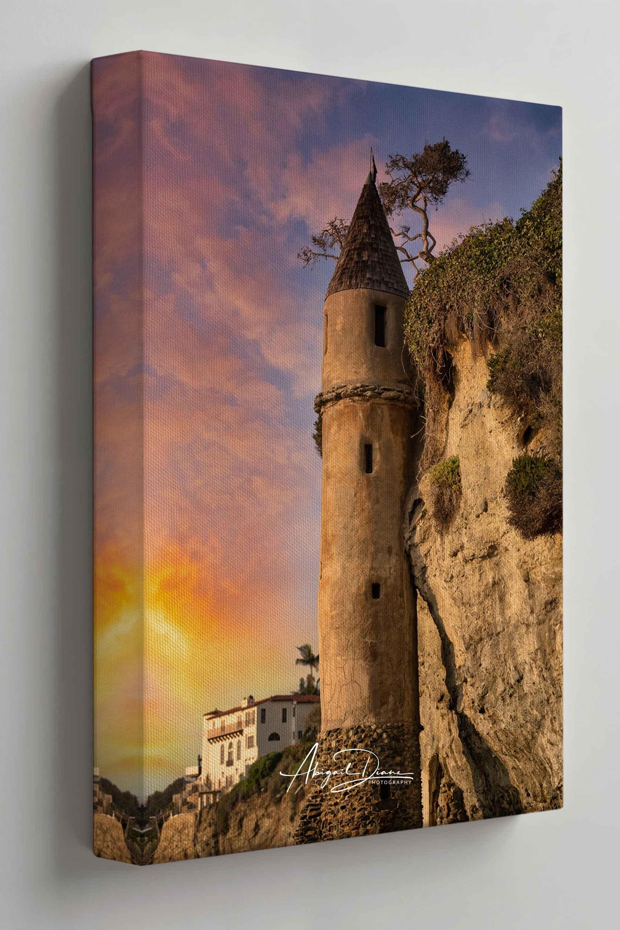 Gallery wrapped canvas print of Victoria Beach Pirate Tower at sunset in Laguna Beach, California, displayed on a soft warm gallery wall. Golden evening light, pastel sky, and rugged coastal cliffs create an elegant coastal wall art mockup.