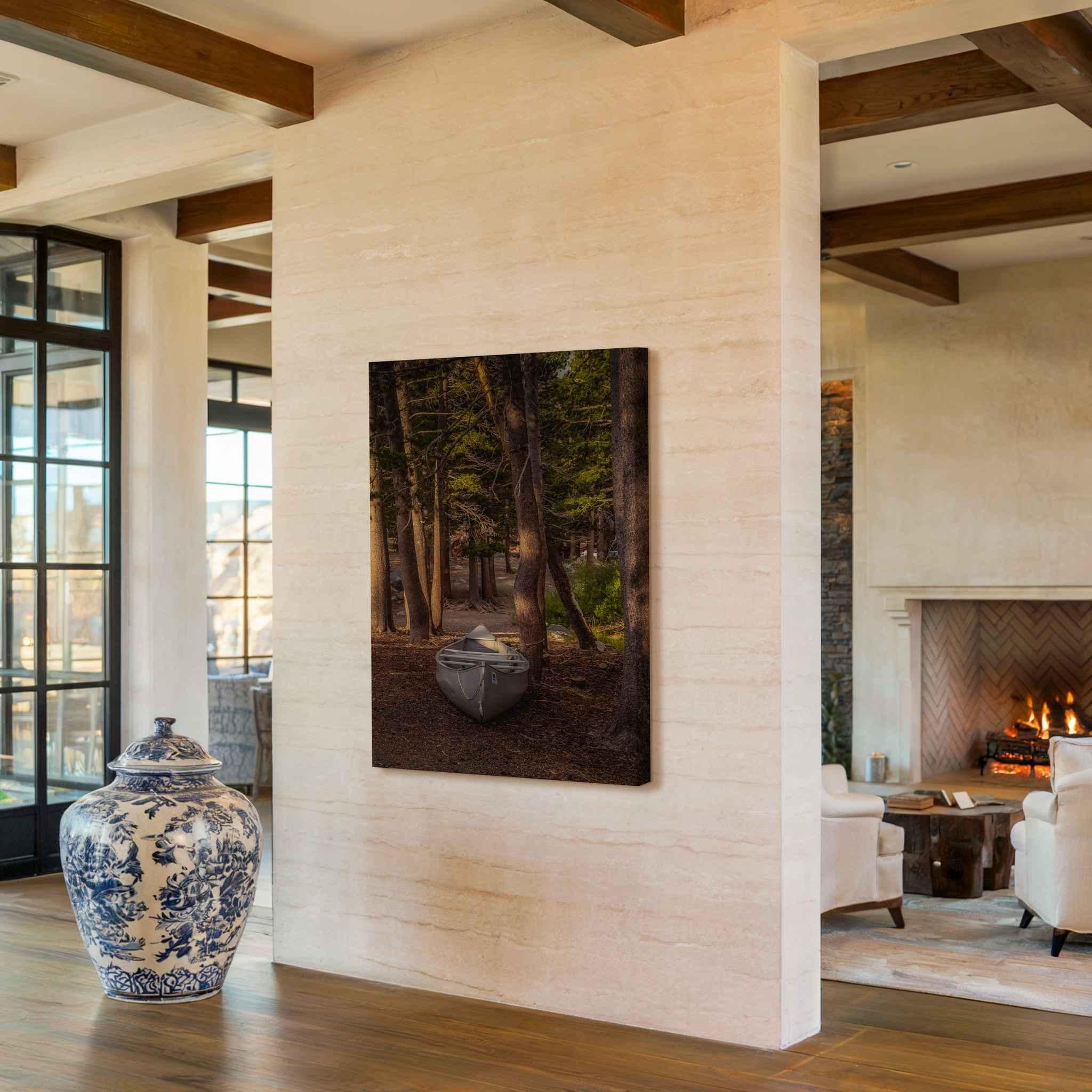 Waiting for the Water canvas print of a canoe resting among the pine trees in Mammoth Lakes, California, displayed in a warm rustic interior.