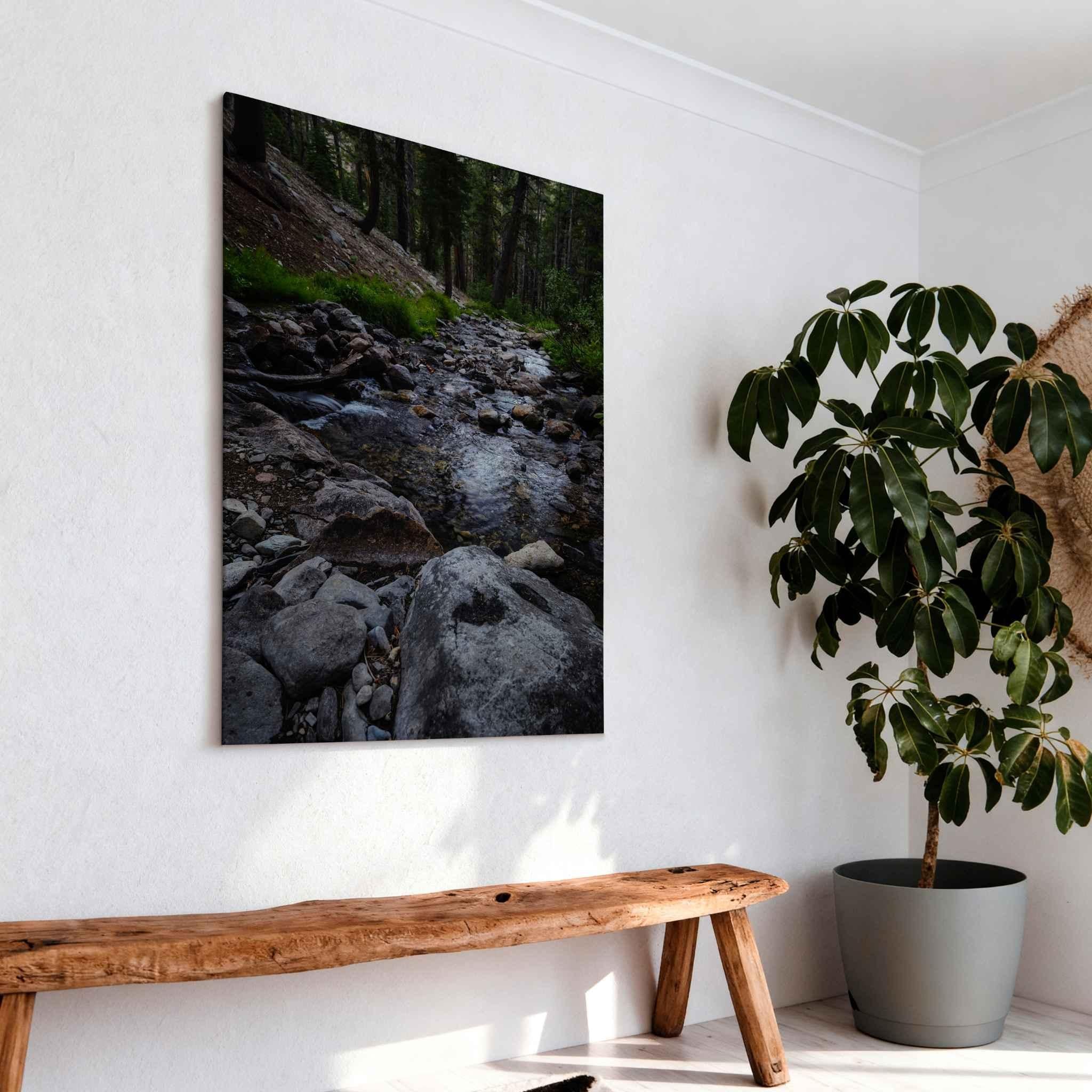 Where Stepping Stones Lead metal print displayed above a rustic wood bench, featuring a rocky mountain stream flowing through the forest in California’s Eastern Sierra.