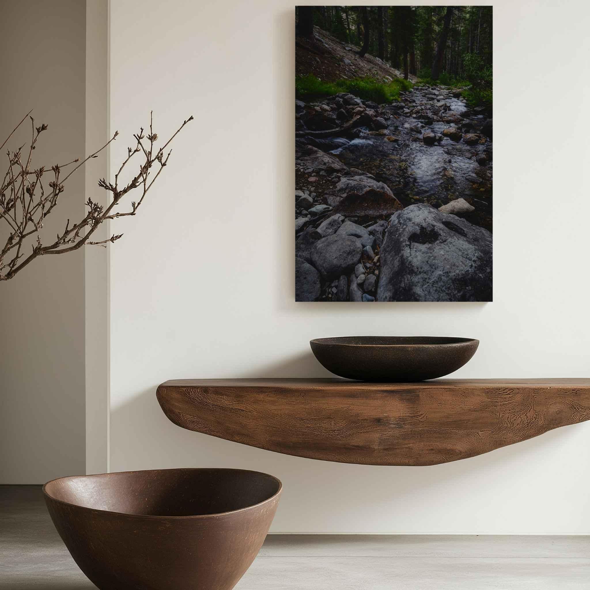 Where Stepping Stones Lead metal print displayed above a natural wood console, featuring a rocky forest stream in the Eastern Sierra near Mammoth Lakes, California.