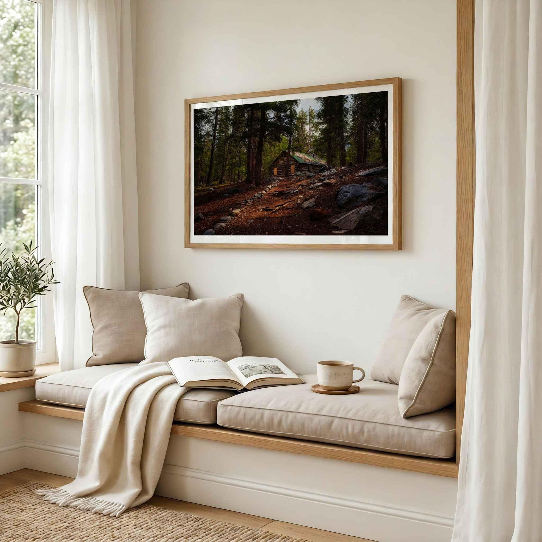 Where the Trail Meets the Past fine art print featuring historic Mahan Cabin near Mammoth Lakes in California’s Eastern Sierra, shown matted in a natural wood frame above a peaceful neutral reading nook.