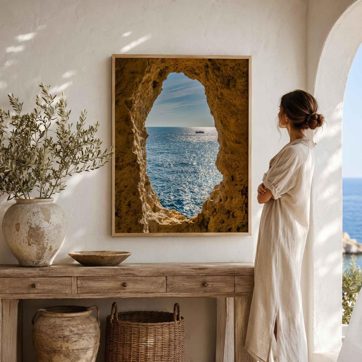 Window to the Atlantic fine art print of Algar Seco, Algarve, Portugal, displayed above a console with a woman standing beside the artwork.