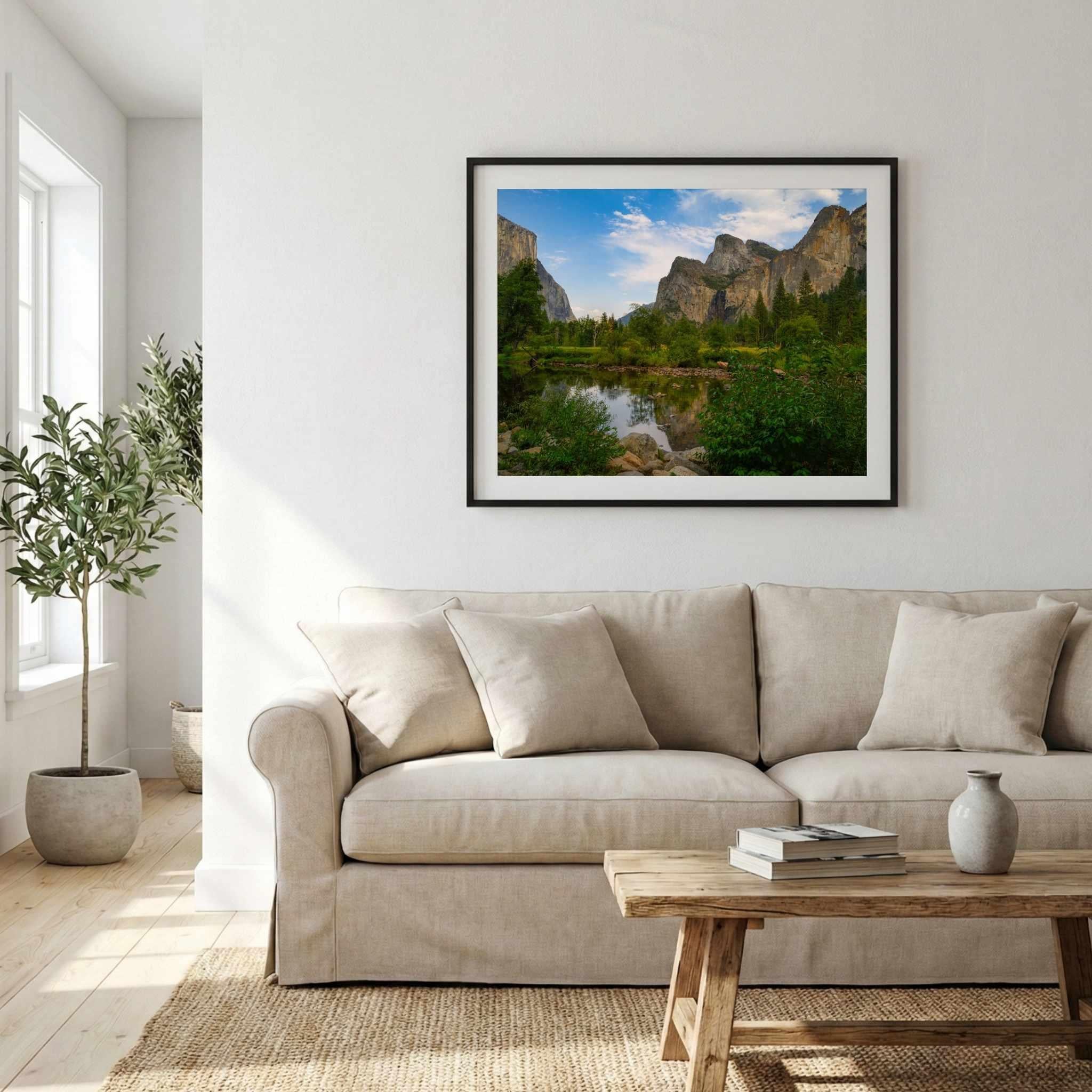 Black-framed Yosemite Valley fine art print by Abigail Diane Photography displayed above a neutral beige sofa in a modern living room with a rustic wood coffee table, soft natural light, and minimalist décor.